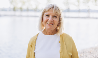 Vanhempi nainen, jolla on lyhyet, vaaleat hiukset, hymyilee kameralle.